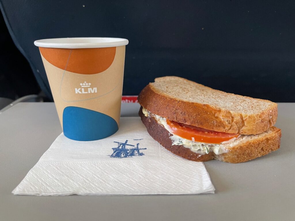 KLM Cuts Free Food And Drinks In Economy To “Strengthen The Warm And Hospitable Experience” a sandwich and a cup of coffee
